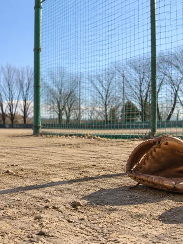 冬の晴れた校庭に張られた防球ネットと野球のグラブ