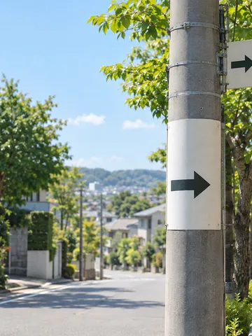 新緑の住宅街に立つ、矢印だけの案内板がついた電柱