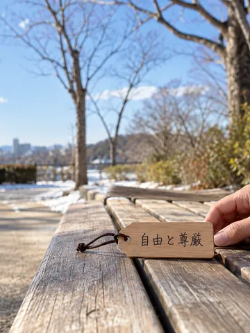 冬の晴れた公園のベンチに置かれた「自由と尊厳」の木札
