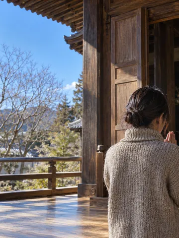 晴れた冬の日に不動堂へ手を合わせる後ろ姿