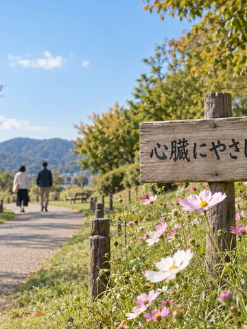 公園の道に立つ「心臓にやさしい町」の木の札とコスモス