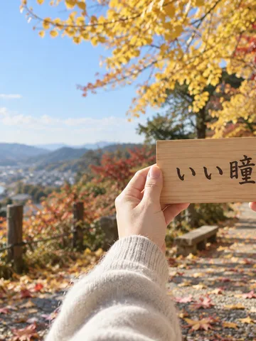 秋の日なたで「いい瞳」と書かれた木の札を持つ手