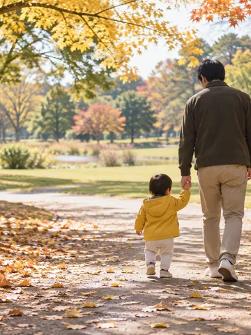 紅葉の公園を子どもと手をつないで歩く父親の後ろ姿