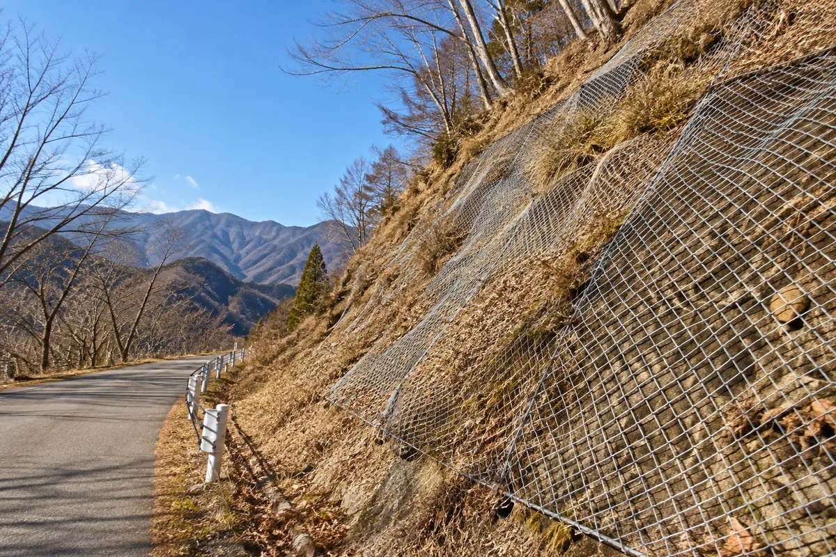 晴れた冬の山の斜面に張られた菱形の金網