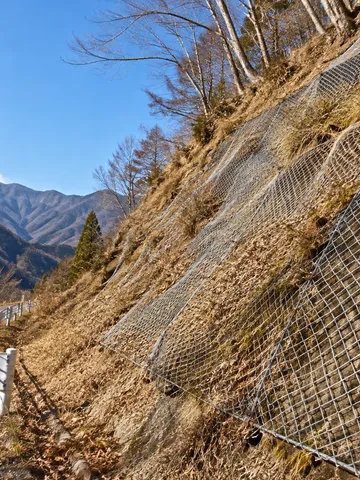 晴れた冬の山の斜面に張られた菱形の金網
