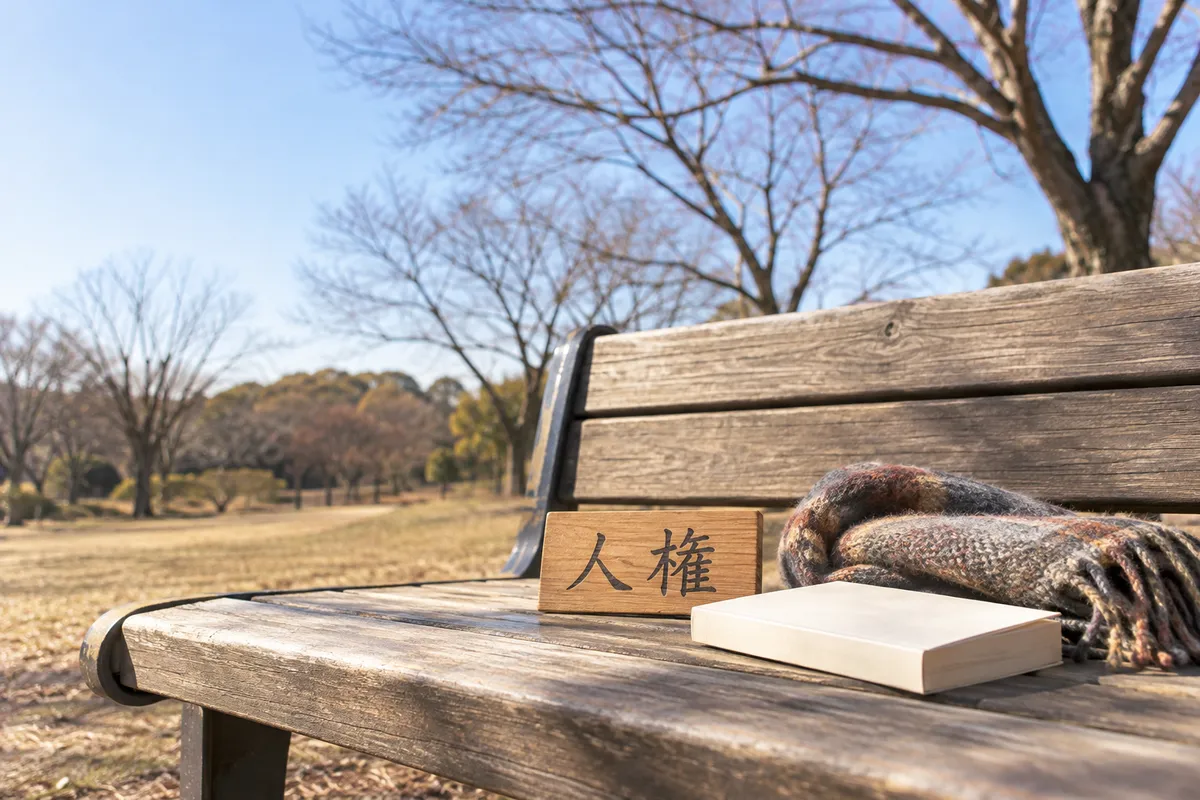 冬の公園のベンチに置かれた「人権」の木の札