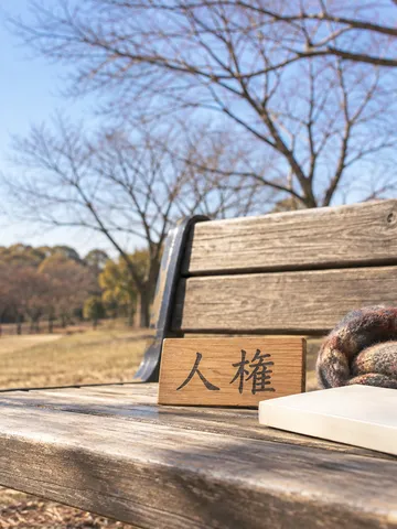 冬の公園のベンチに置かれた「人権」の木の札