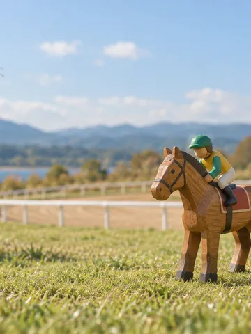 芝の上に並ぶ木製の競走馬のおもちゃとミニチュアのコース