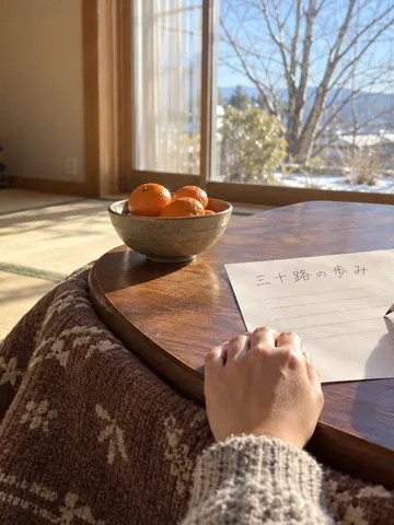 こたつの上のみかんと「三十路の歩み」と書かれた紙