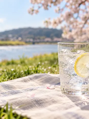 春の日なたに置かれた氷入りの透明な炭酸飲料のグラス