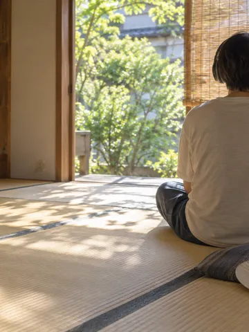 畳の部屋でヘッドホンでラジオを聴く後ろ姿