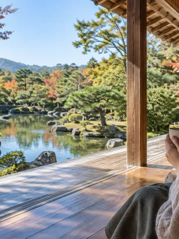 縁側から紅葉し始めた旅館の庭を眺める後ろ姿