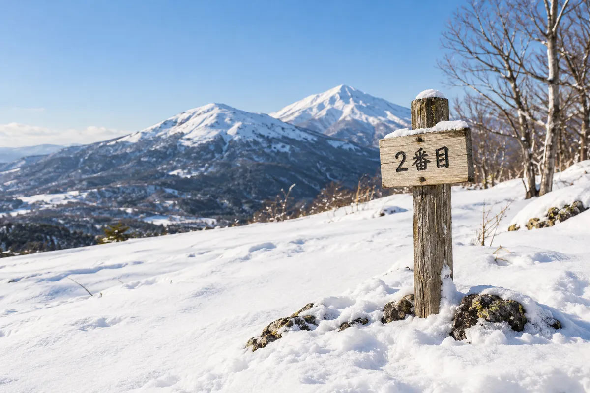 晴れた雪山に立つ「2番目」と書かれた木の札
