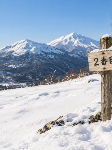 晴れた雪山に立つ「2番目」と書かれた木の札