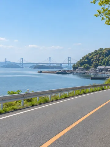 瀬戸大橋が遠くに見える海沿いの道