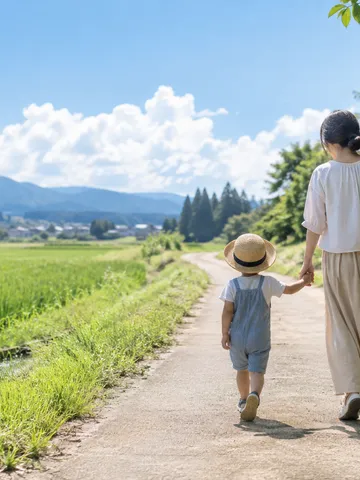 夏の野道を手をつないで歩く親子の後ろ姿