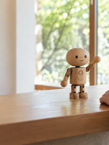 受付カウンターで手を挙げる木製のロボットのおもちゃ