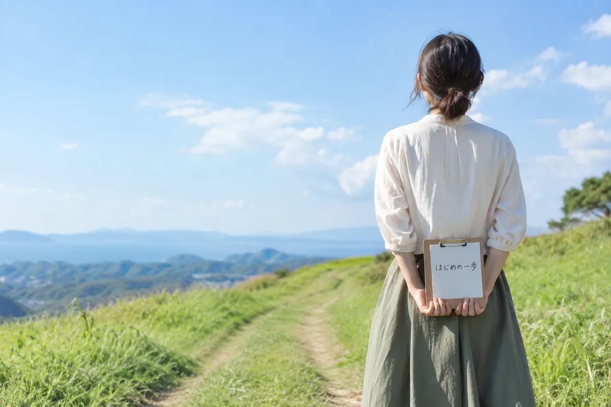 丘の小道の始まりで「はじめの一歩」と書いたメモを持つ後ろ姿