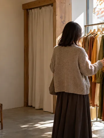 秋色の服が並ぶ店で袖に触れる後ろ姿