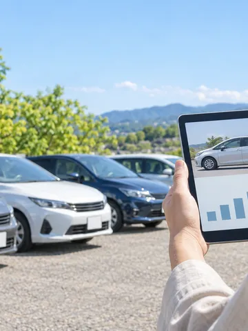中古車が並ぶ屋外でタブレットを持つ手元