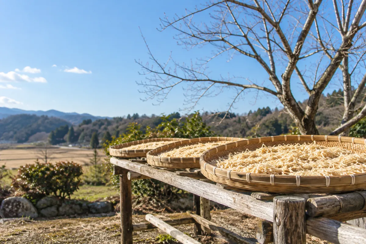 青空の下、竹のざるで干される千切り大根