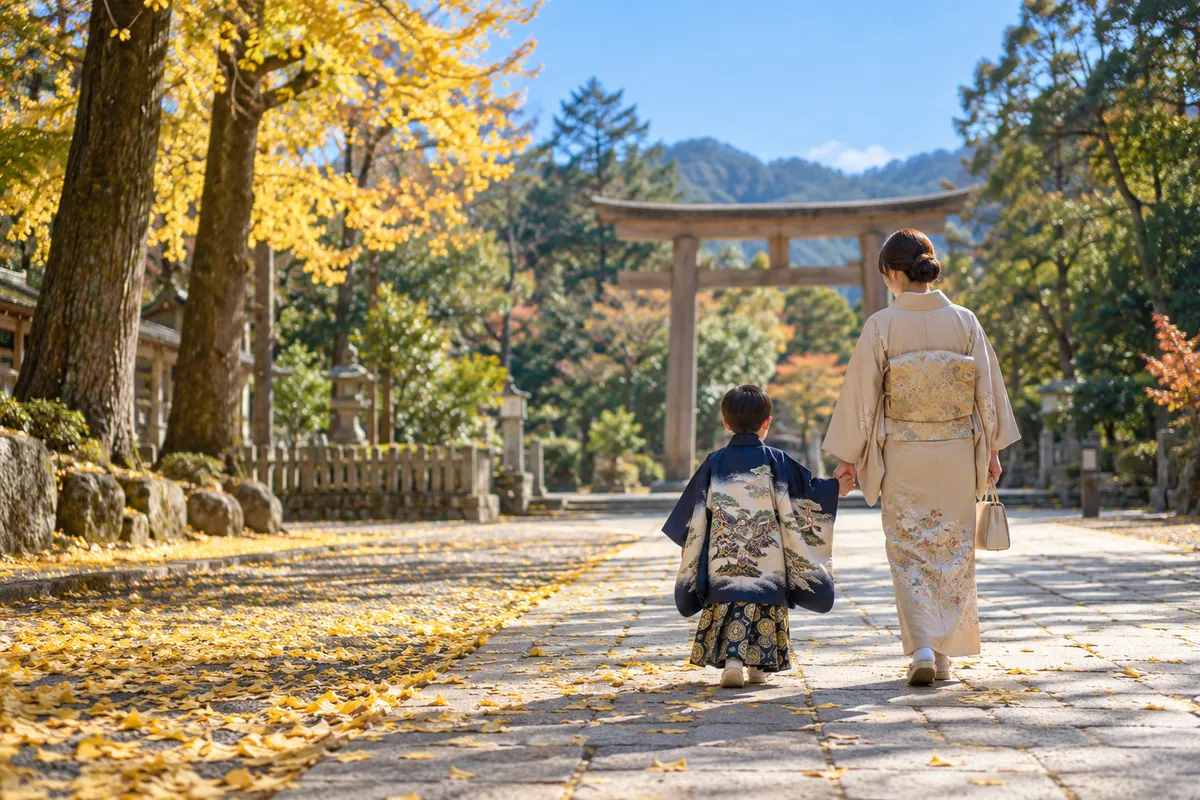 紅葉の境内を手をつないで歩く着物姿の子どもの後ろ姿