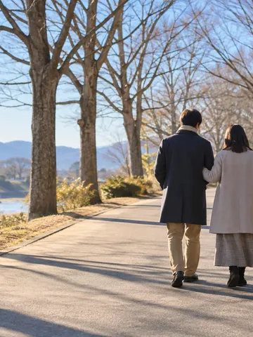 冬の日なたの並木道を歩く二人の後ろ姿