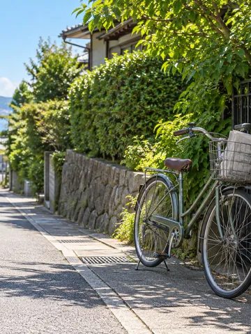 夏の昼の門前に停めた、新聞を積んだ配達用自転車