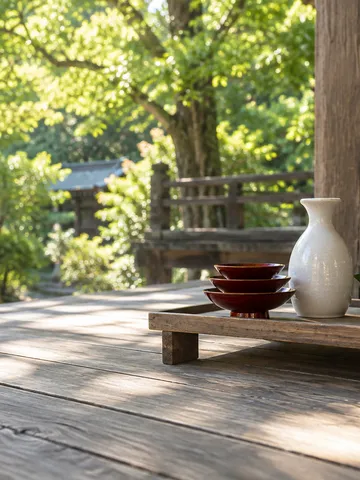 神社の縁側に置かれた三つ重ねの朱の杯と玉串