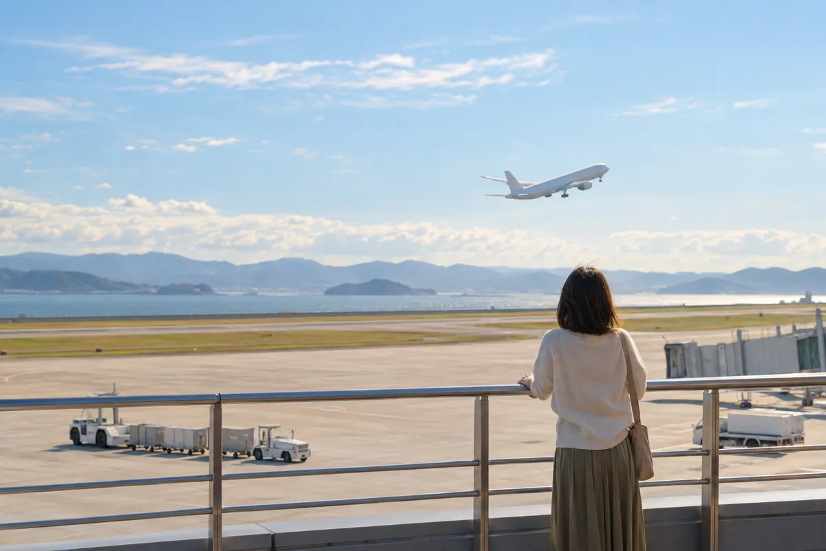 空港の展望デッキから離陸する飛行機を眺める