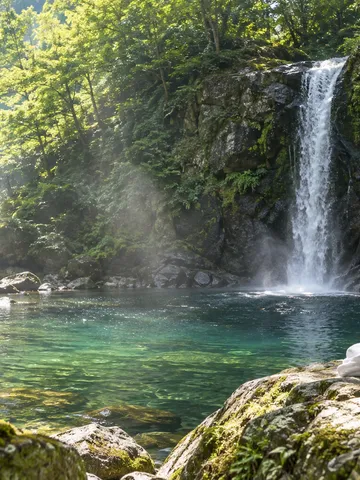 夏の森の滝と岩の上に置かれた白い行衣