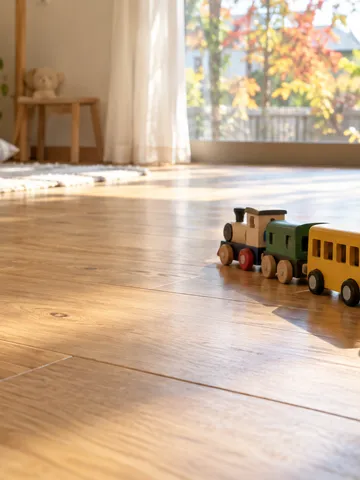 床に並んだミニカーや電車のおもちゃと子どもの手