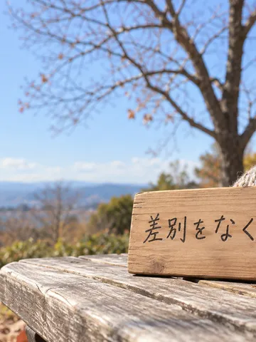 冬の日なたのベンチに置かれた木の札とマフラー