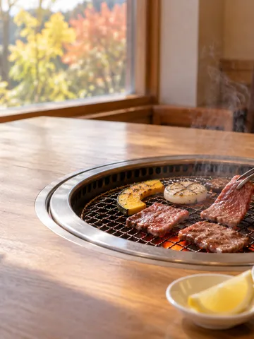 炭火の網で焼かれる牛肉とタレの小皿